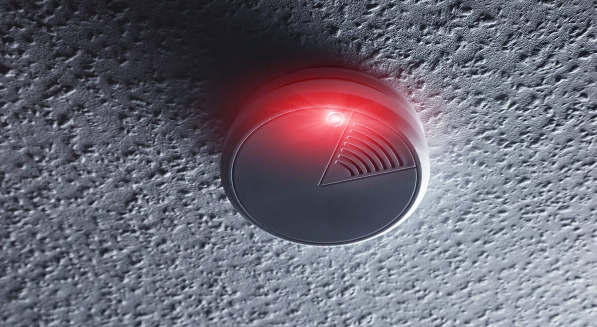Smoke detector mounted on roof in house with red warning light. ideal for websites and magazines layouts