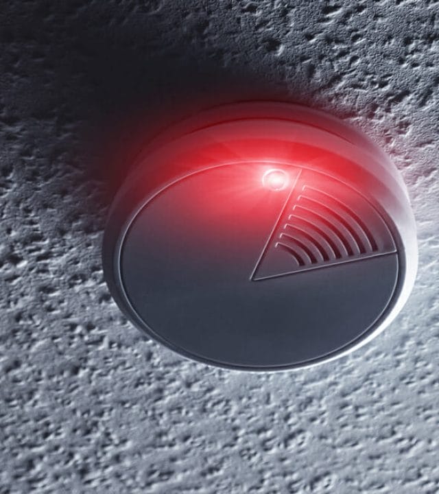 Smoke detector mounted on roof in house with red warning light. ideal for websites and magazines layouts